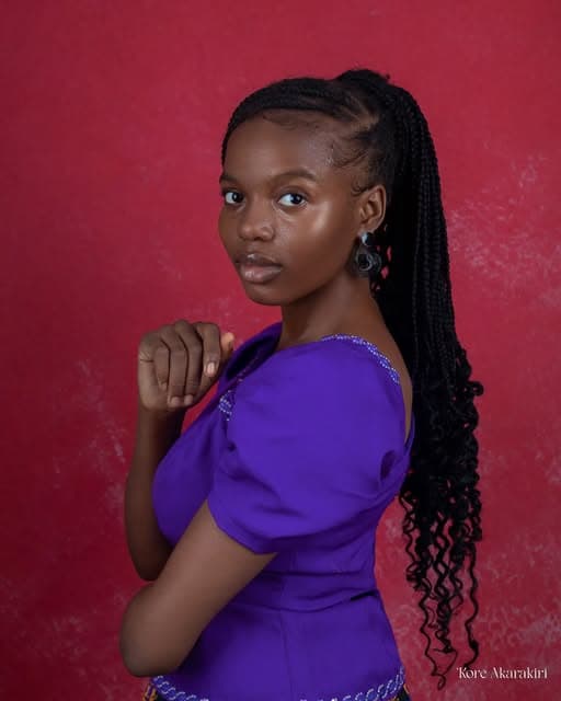 Woman in purple on a red backdrop, photographed by Kore Akarakiri